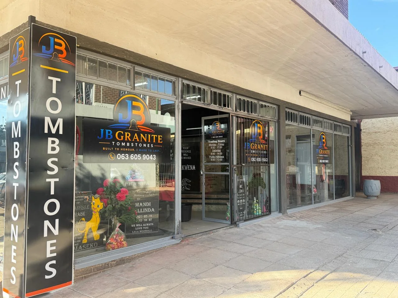 Showroom window with finished granite memorials and the JB Granite logo